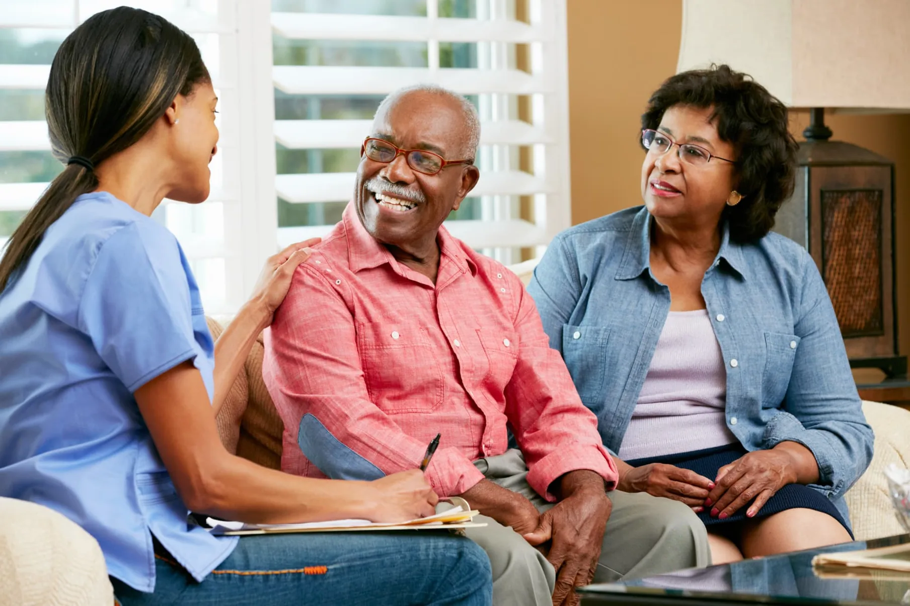 An advisor sitting with an older couple in their living room, talking through paperwork together.