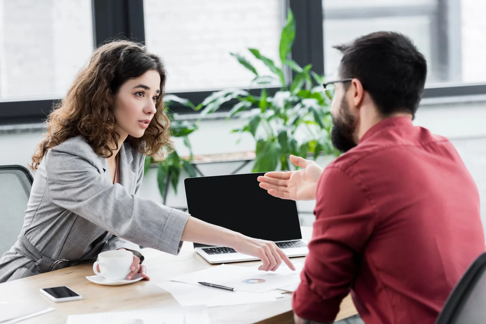 Two colleagues discussing benefits paperwork across a desk in a bright office.