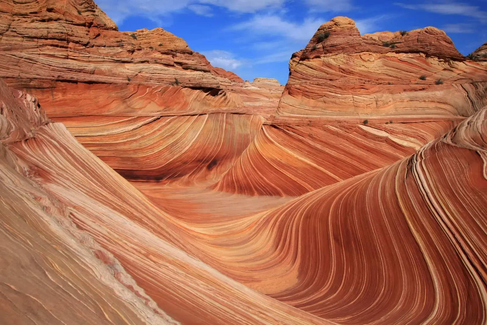 Sweeping bands of red and cream sandstone curving through a desert rock formation under a blue sky.
